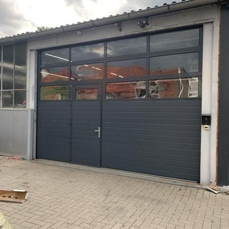 ConDoor Industrie-Sektionaltor ISO40, Typ S40, RAL 7016 Anthrazitgrau, mit Schlupftür, Rahmen der Tür und Fenstersektionen in Torfarbe pulverbeschichtet